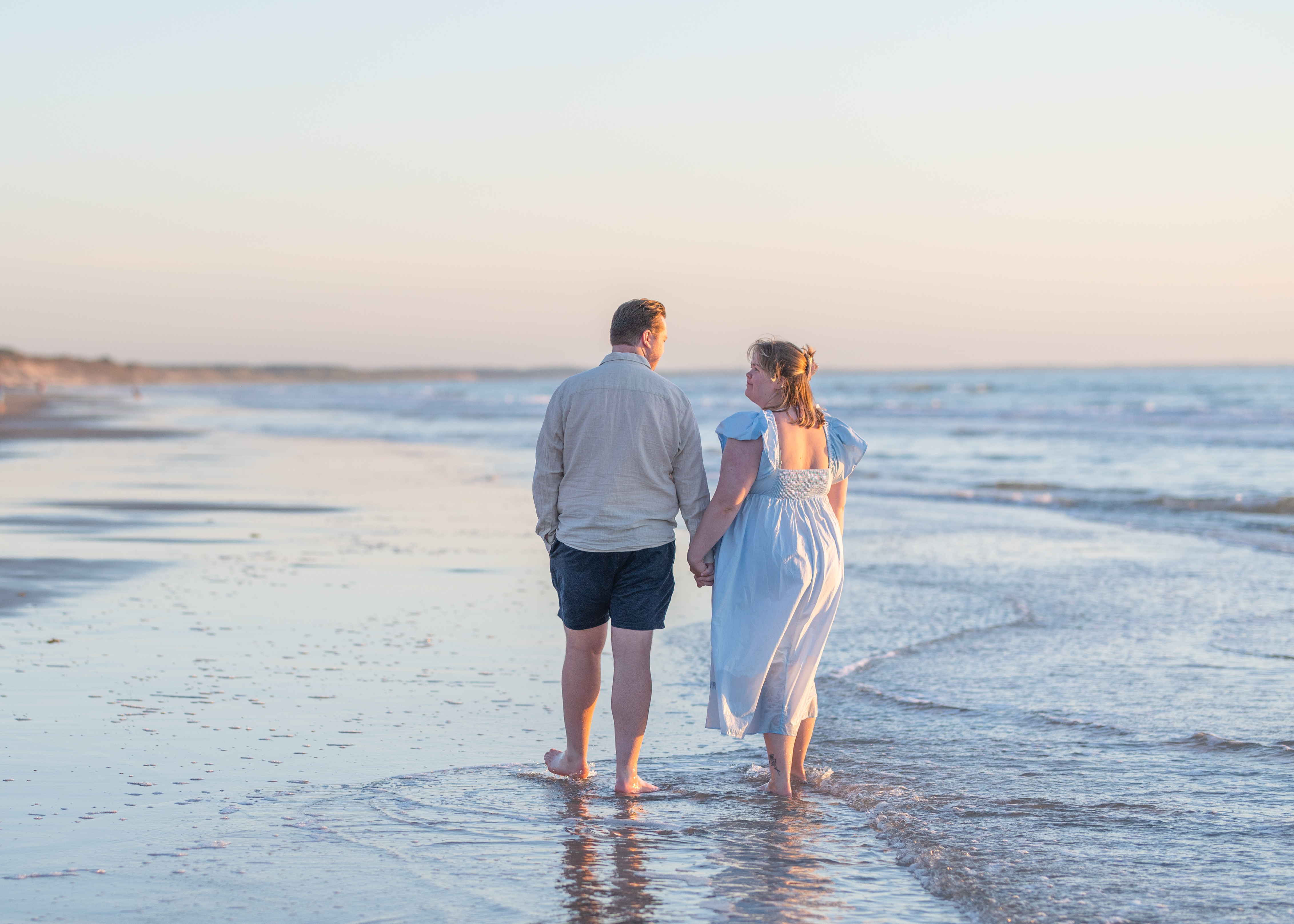 Parfotografering - Kjærestepar som går langs en strand, holder hender